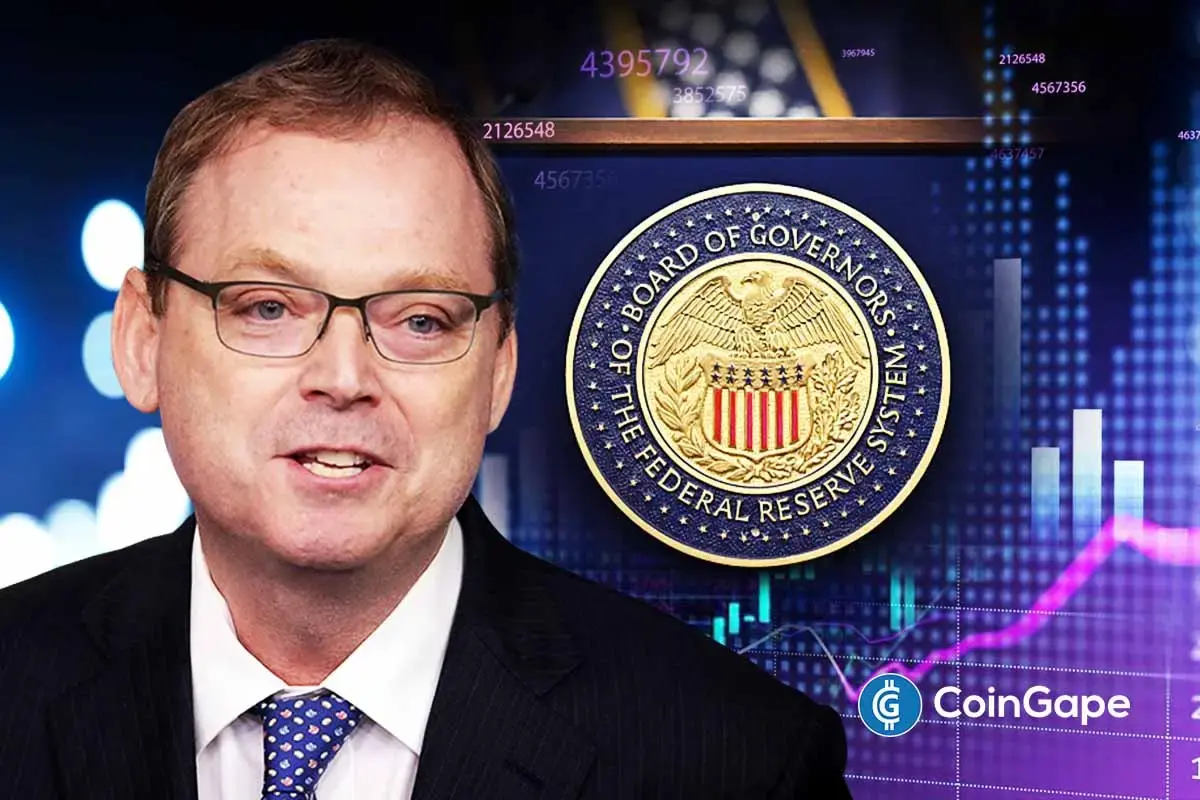 Kevin Hassett appears with Federal Reserve seal and rising market chart as Fed chair race shifts toward Wall Street.
